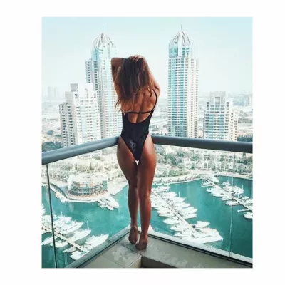 Egyrészes fürdőruha Dubaiban: hol lehet vásárolni, és mit kell viselni? : Nő egy darabból álló fürdőruhát visel a Dubai kikötő felett